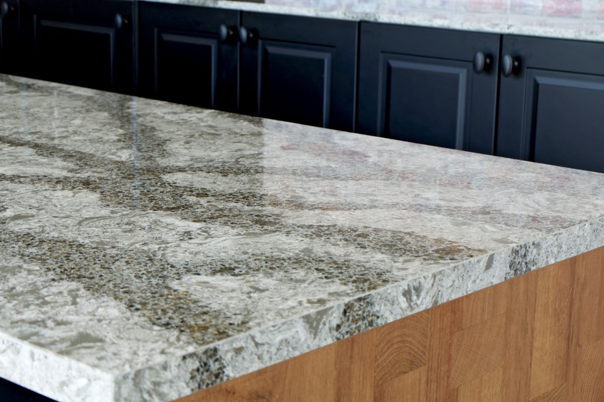 A gray quartz countertop with black cabinets in the background.